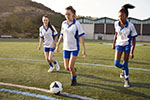Three teenage girls practicing soccer.