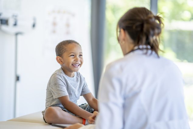 A young boy laughing while talking with a healthcare professional