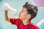 A young boy drinks water from a sports bottle.