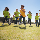 A group of children run across an open playground.