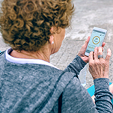 An older woman exercises with the help of a mobile phone.
