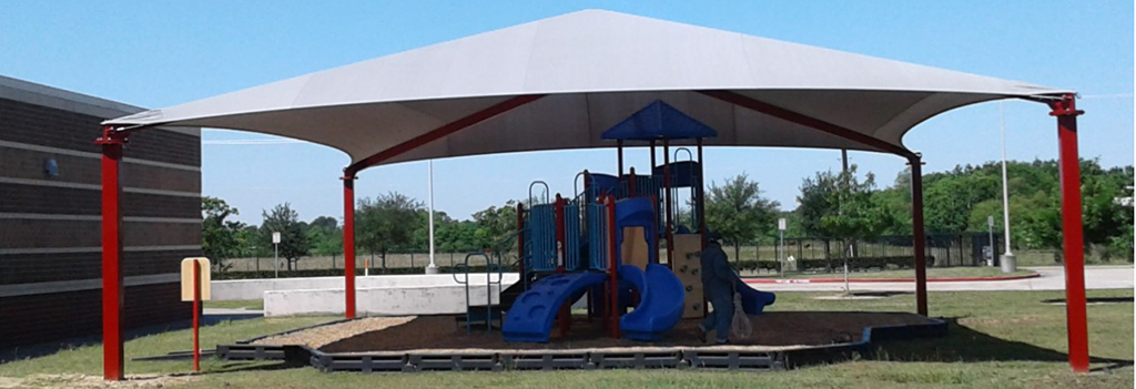 A sunshade structure over playground equipment at an elementary school.