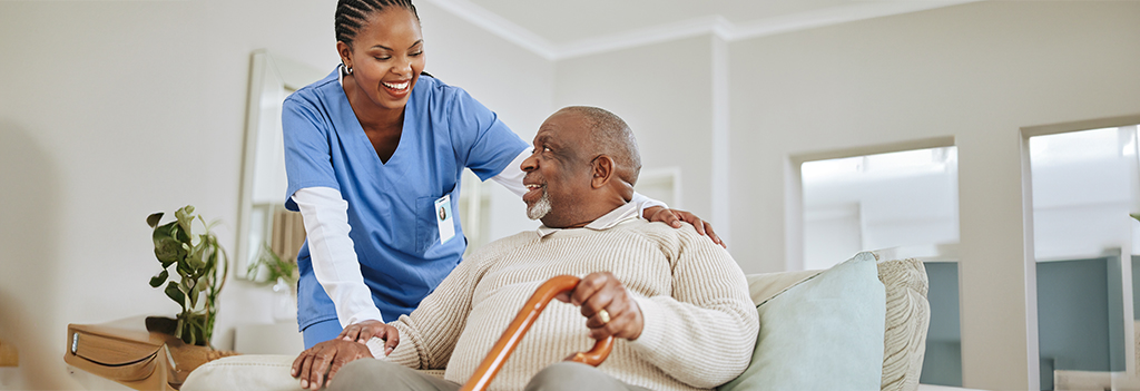 A female health care worker talks with an elderly male patient