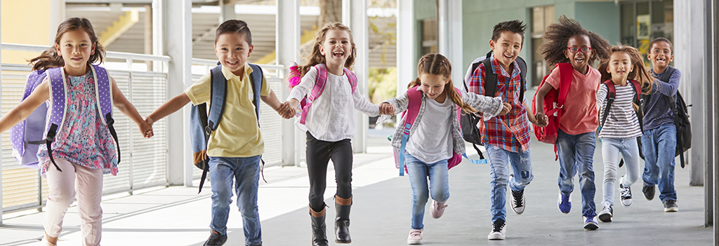 Elementary school kids run down a hallway holding hands