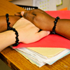 Four hands esting upon each other. Each has a bracelet of black coral around the wrist.