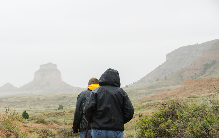 Two people walking an outdoor trail in a misting rain.