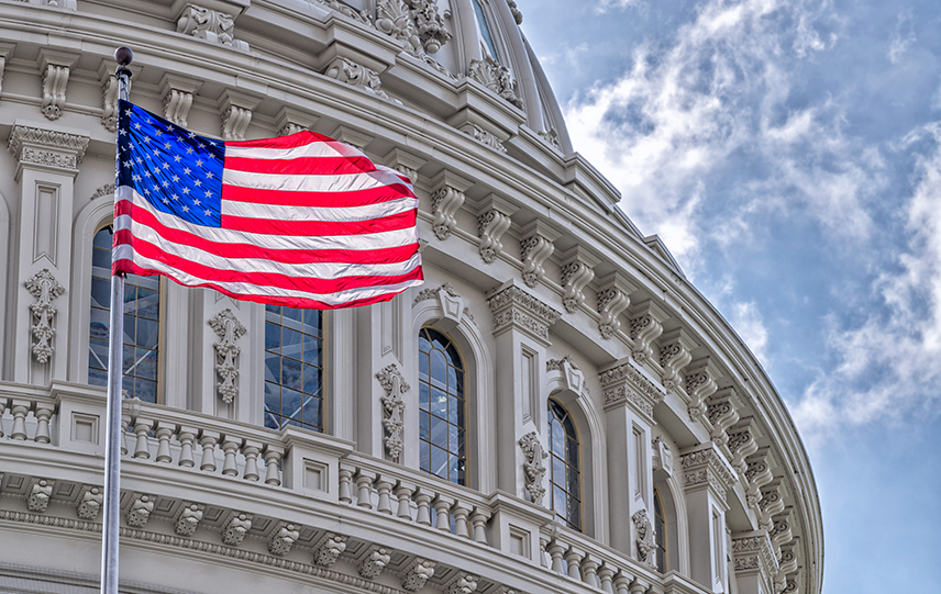 The flag of the United States flies outside of the dome of the U.S. Capitol building.