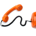 A red telephone handset connected to a red base by a black cord