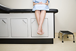 A woman sits on a doctor's exam table.