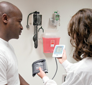 A nurse shows a male patient the readout of a digital blood pressure monitor