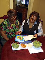 Two women at a table review educational materials,  represent community health workers engaging to prevent cardiovascular disease.